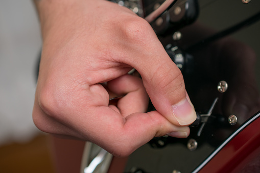 Close-up of a hand switching the pickups with the pickup selector switch on an electric guitar. Unrecognizable person, music concepts