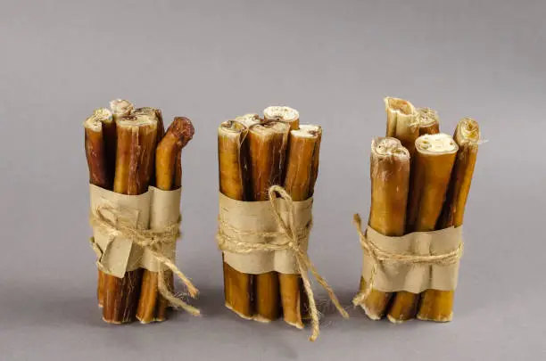 Photo of Gray-brown composition with dog treats. Bully sticks wrapped in