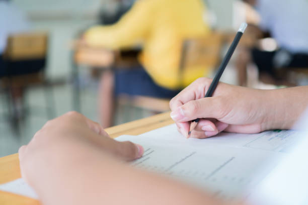istock School in Exam, Hands Students learning Exams in Classroom Pupil  student's read note taking admission test and thinking writing on answer papers with classmates in high school or college educaional 1331864717