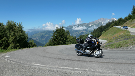 La rosière, France. July 18. 2021. Winding mountain road with a motorcycle that passes in a bend.