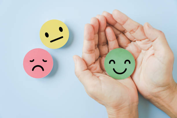 smiling face in hand on blue background  satisfaction survey ,good feedback rating and positive customer review, comment, experience, mental health assessment concept stock photo