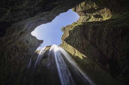 Gljúfrafoss Waterfall in hidden Gorge from below against blue summer sky. Gljúfrafoss is located close to the famous Seljalandsfoss in Hamragarðar. It is a small waterfall north of the larger falls of Seljalandsfoss in Iceland. View from the Gljufrabui waterfall pool up to the sky. Hamragarðar, Seljalandsfoss, Route 1, South Central Iceland, Nordic Countries, Northern Europe.