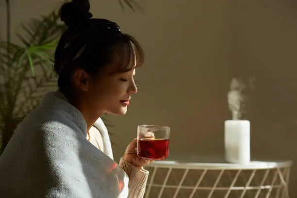 Photo of A young Asian woman relaxing at home drinking fruit tea