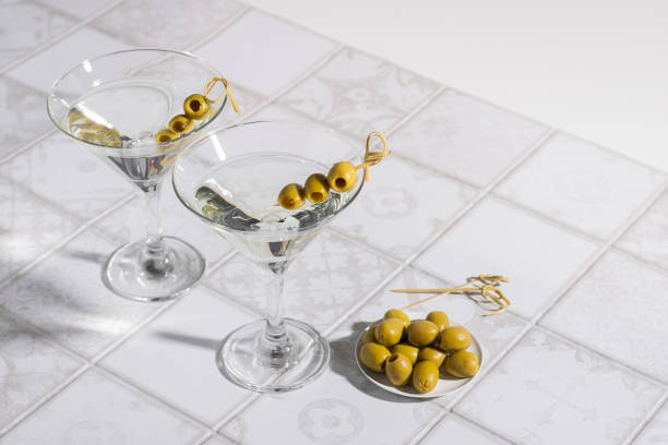 타일 테이블에 올리브와 마티니 칵테일. 우아한 유리에 얼음이 있는 알코올 클래식 음료 - gin tonic water martini olive 뉴스 사진 이미지