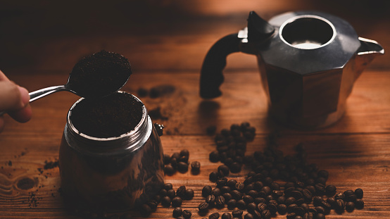 Man holding a spoon of ground coffee.