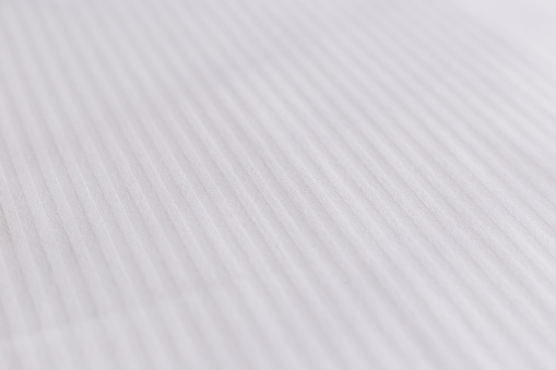Elegant textile on bed. Striped pattern on a snow-white bedsheet