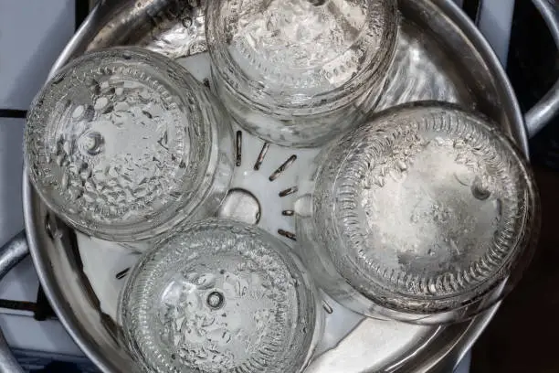 Glass jars in the stainless steel pot over the steamer during steam sterilization for the home canning, top view