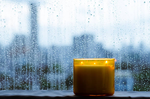 Burning aroma candle puts near by window that have rain drop