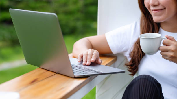 istock a beautiful young asian woman drinking coffee while using and working on laptop computer in the outdoors 1331898171