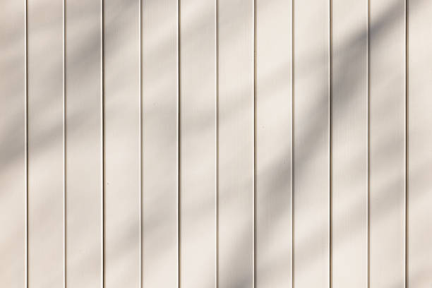 Off-white wooden fence with shadows from trees..