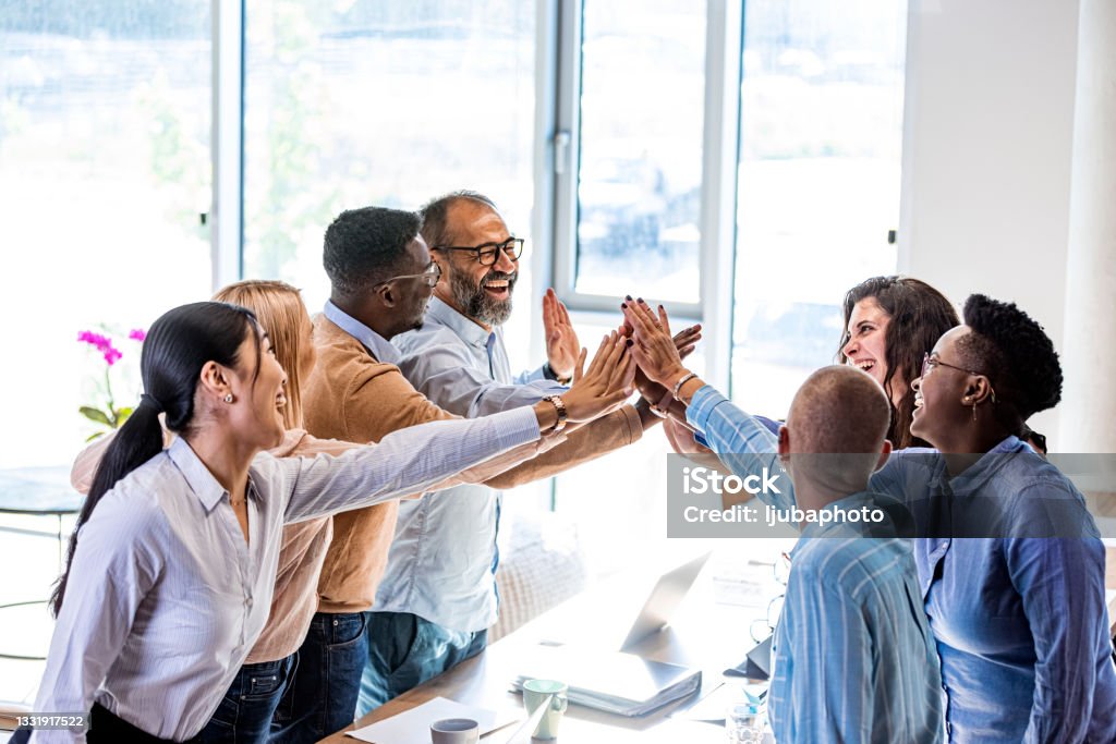 Business is winning when we stick together Shot of a group of young and mature businesspeople joining hands in solidarity in a modern office Community Stock Photo
