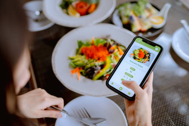 la tecnologia rende la vita molto più facile per la giovane donna asiatica che utilizza un dispositivo di app mobile su smartphone per effettuare un ordine alimentare in un ristorante. - smart mobile foto e immagini stock