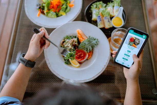 istock Technology makes life so much easier for young Asian woman using mobile app device on smartphone to place a food order in a restaurant. 1331920616