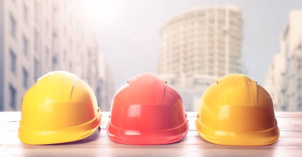 istock Hard hats on wooden surface at construction site with unfinished building. Banner design 1331923846
