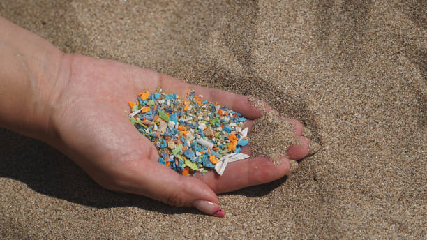 Side view of a hand holding microplastics. Non-recyclable materials. Selective focus of microplastics. stock photo