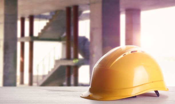 istock Hard hat on white wooden surface at construction site with unfinished building. Space for text 1331924523