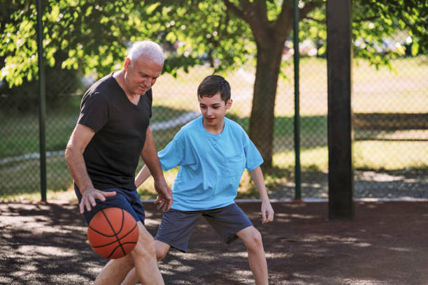 Grandfather And grandson playing basketball. stock photo