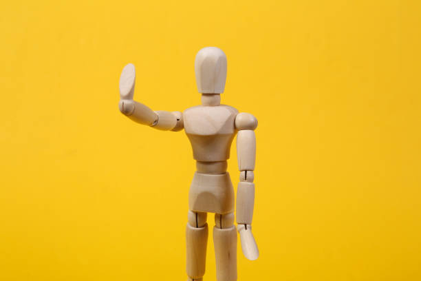 istock Wooden puppet shows hand stop isolated on yellow background 1331926527