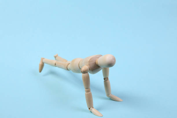 istock Wooden puppet push ups on a blue background. Sport concept 1331926601