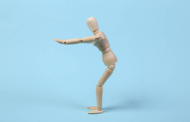 istock Wooden puppet practices squats against blue background. Aerobics concept 1331926676