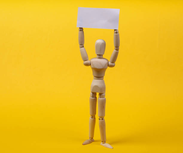 istock Wooden mannequin puppet standing with blank sign protesting on yellow background 1331927231