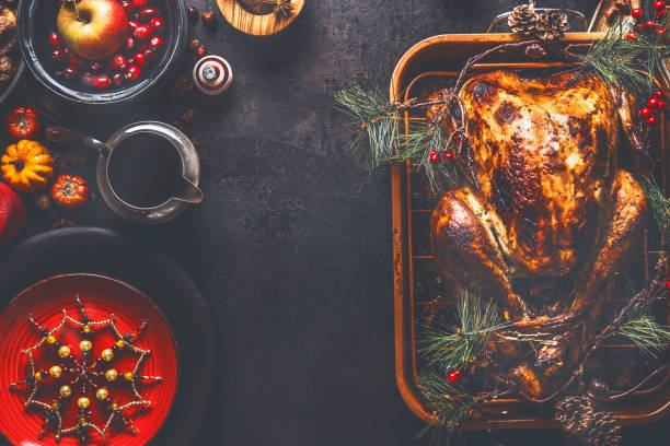 istock Christmas dinner background. Roasted stuffed turkey served with fresh cranberries, pine branches and sauce on rustic background 1331931008
