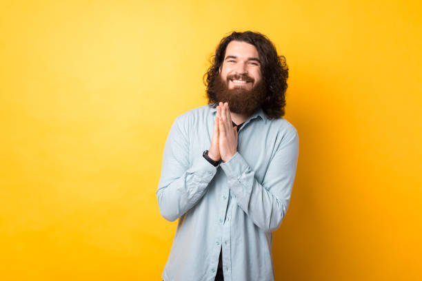 istock Please, do me favour. Bearded man smiles with begging expression, keeps palms pressed together, has big hope 1331932202