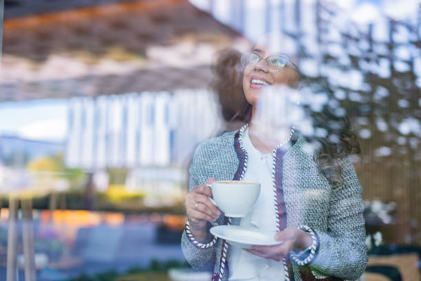 istock Young woman drinking coffee and looking through window 1331936172