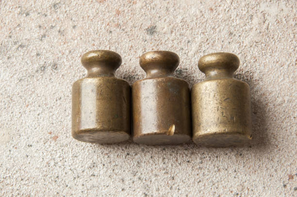 Three antique bronze weights for scales on concrete background. Copy space for text and food photography props.