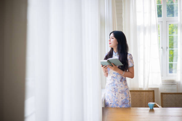 istock Young women reading a book by window 1331938746