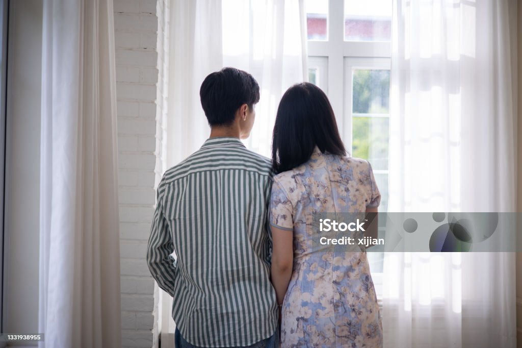 Young asian couple looking through window Japanese Ethnicity Stock Photo