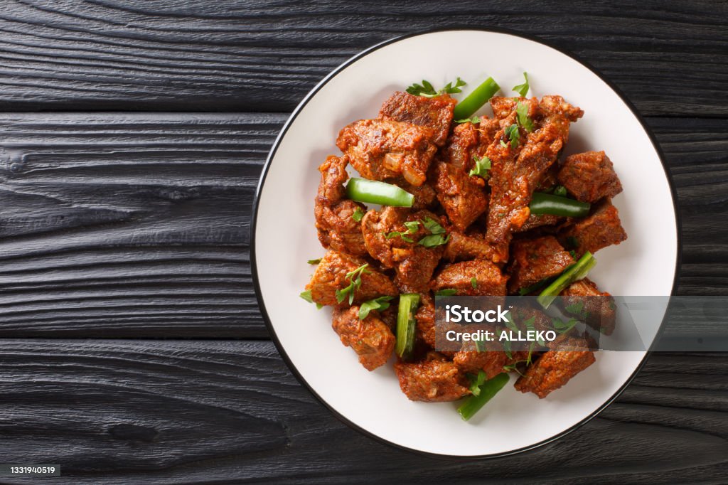 Ethiopian cuisine Tibs fried beef meat in a spicy vegetable sauce close-up in a plate. Horizontal top view Ethiopian cuisine Tibs fried beef meat in a spicy vegetable sauce close-up in a plate on the table. Horizontal top view from above Fried Stock Photo