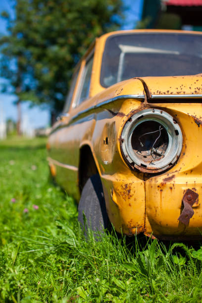 Old yellow wrecked car in vintage style. Abandoned rusty yellow car. Old yellow wrecked car in vintage style. Abandoned rusty yellow car. Close-up of the headlights of the front view of a rusty, broken, abandoned car near the house. Concept of abandoned used car. distressed rusty vintage pickup truck close up detail stock pictures, royalty-free photos & images
