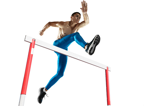 Steeplechase. Young male athlete, runner running, jumping isolated on white studio background. Muscular, sportive man. Concept of sport, action, motion and healthy lifestyle, wellness. Bottom view.