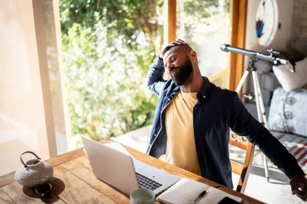 Mature man stretching while working at home