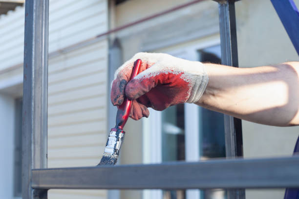 a man's hand in a white and red glove paints a metal structure with a brush