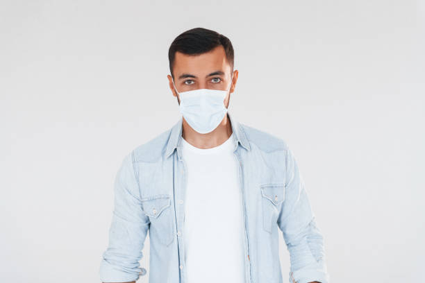 istock In protective mask. Young handsome man standing indoors against white background 1331953451