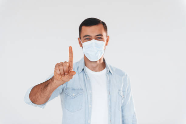 istock In protective mask. Young handsome man standing indoors against white background 1331955227