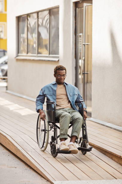 istock Young man in wheelchair moving down ramp 1331957234