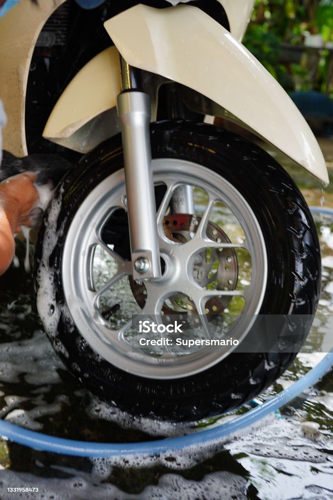 Washing a motorbike wheels Close-up of a man's hand washing a motorbike wheels in home Motorcycle Stock Photo
