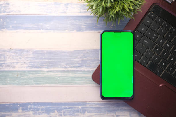 istock smart phone with empty screen, laptop on wooden background 1331958525