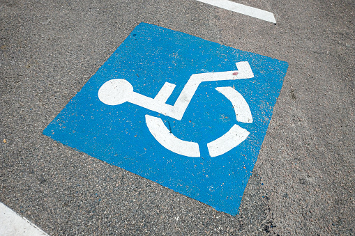 symbol of a parking space for the disabled on the paved floor of a parking lot