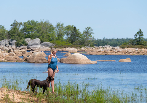 A mature woman with her dog getting ready to swim in a lake