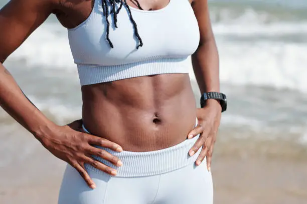 Cropped image of strong fit female body with well- defined abs