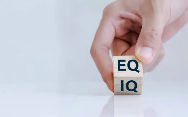 Photo of Close up of hand change wooden cube with word IQ to EQ. Emotional intelligence and intelligence quotient