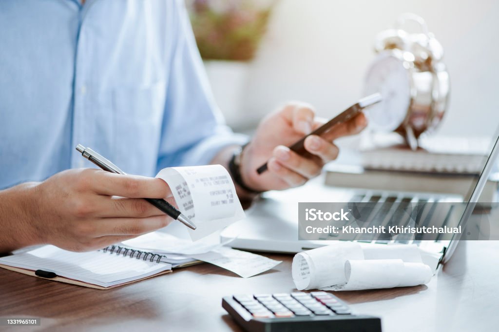young man holding pen with bills working for calculate business data, taxes, bills payment, Start up counting finance. accounting, statistics, and analytic research concept Tax Stock Photo