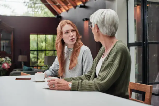 Photo of Shot of a young woman having coffee with her elderly mother at home