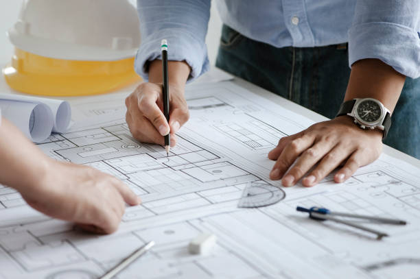 istock close up of team engineer or architect meeting for project working with partner and engineering tools on model building and blueprint in working site. Construction concept 1331966404