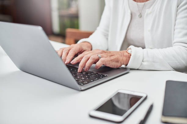 tiro de uma mulher idosa irreconhecível usando um laptop em casa - internet learning computer keyboard computer - fotografias e filmes do acervo