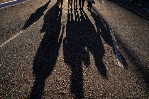 Shadow of a family or friends group walking in a street in the sunset